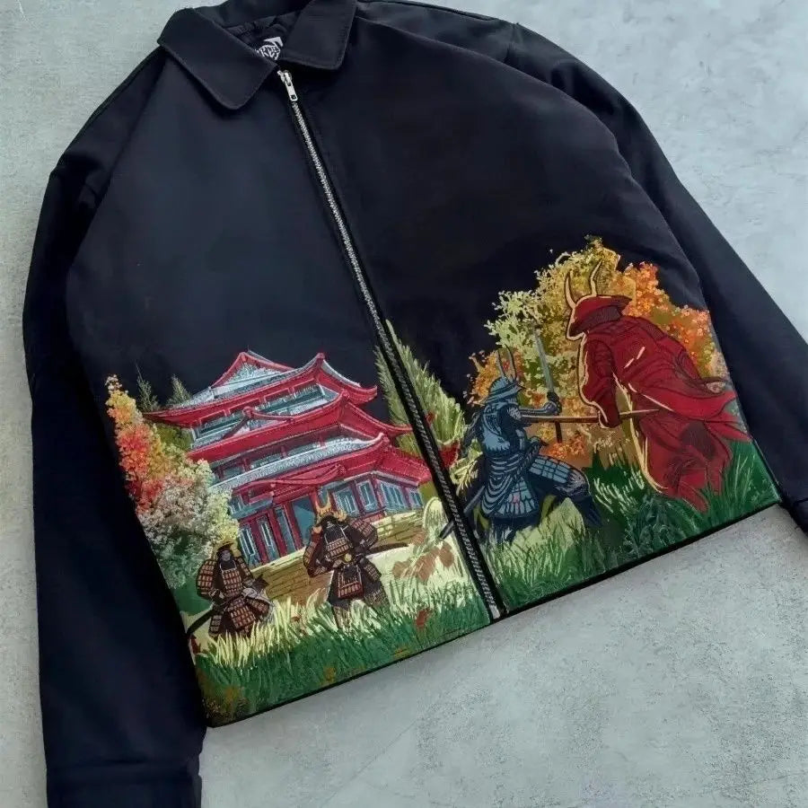 Black jacket with embroidered samurai design on a gray surface